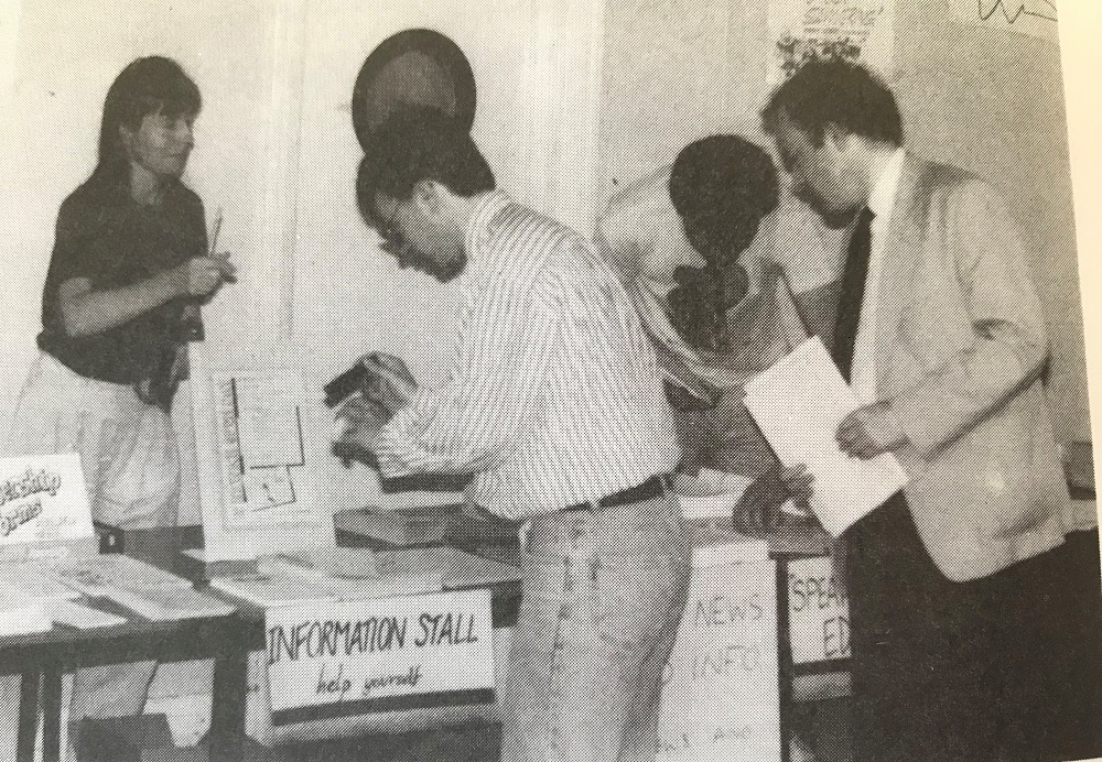 A black and white image of people at an information stand