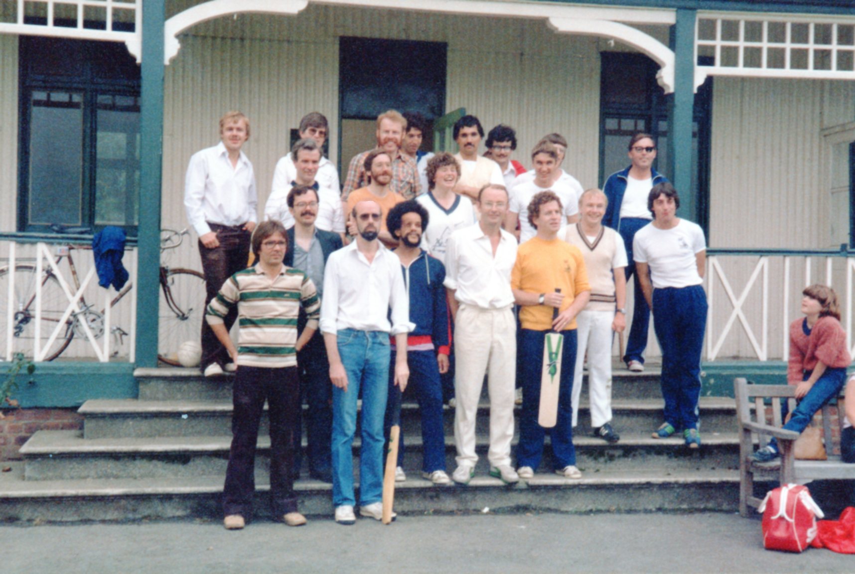 An old photograph of a group of people standing outside a cricket pavilion