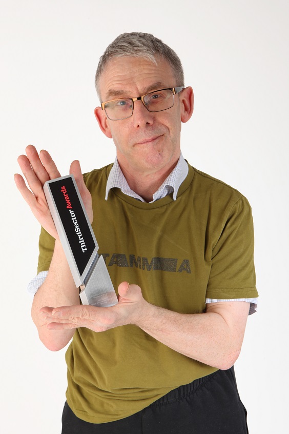 A man holding an award and looking at the camera