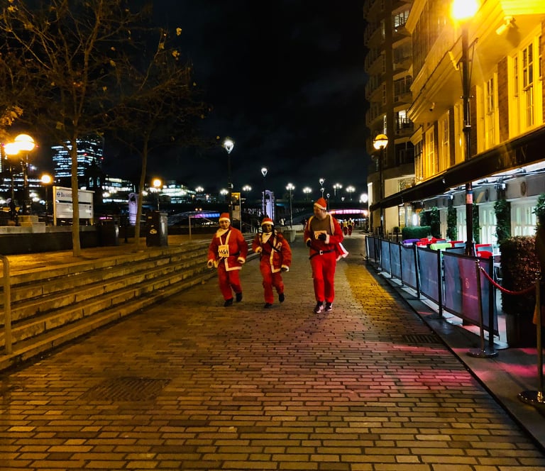 Three people running dressed as Father Christmas