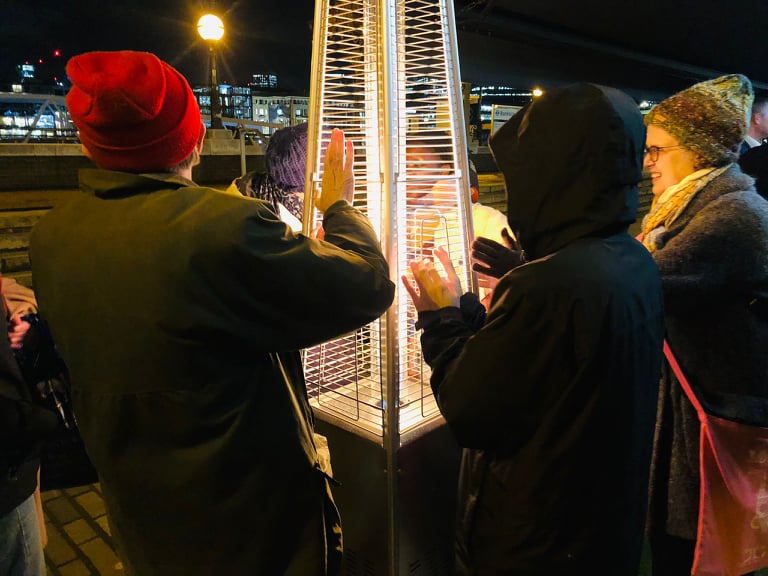People warming their hands on an outdoor heater