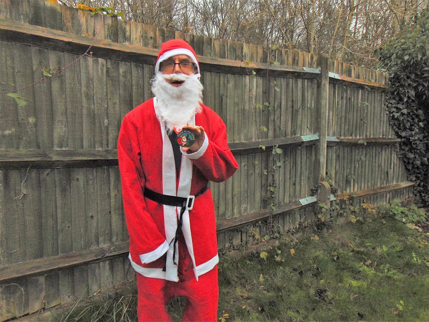 A man dressed as Father Christmas looking at the camera and holding a medal