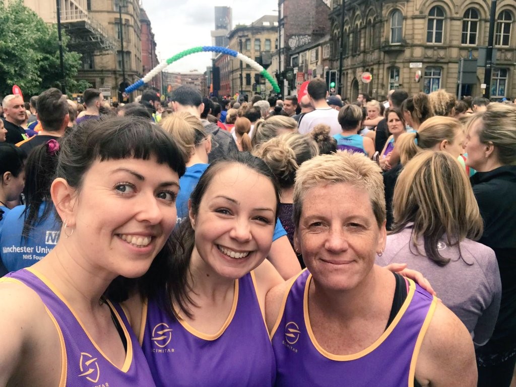Three women in running vests looking at the camera and smiling